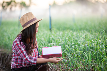 Farmers smiling women, recording happy and happy results in the onion plots with notebook