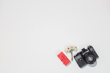 Minimalistic flat lay composition with retro camera, red gift box and spring field flower on white background. Trendy flat lay mockup for bloggers, designers, photographers, etc