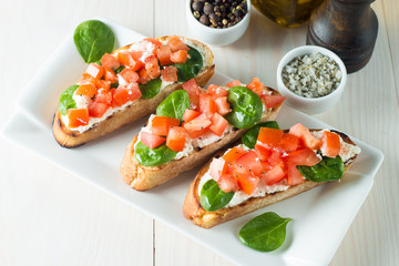 Tomato and cheese fresh made bruschetta. Italian tapas, antipasti with vegetables, herbs and oil on grilled ciabatta and baguette bread. Sandwich.