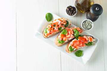 Tomato and cheese fresh made bruschetta. Italian tapas, antipasti with vegetables, herbs and oil on grilled ciabatta and baguette bread. Sandwich.