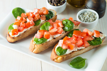 Tomato and cheese fresh made bruschetta. Italian tapas, antipasti with vegetables, herbs and oil on grilled ciabatta and baguette bread. Sandwich.
