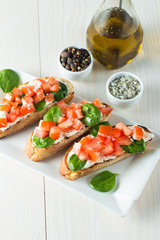 Tomato and cheese fresh made bruschetta. Italian tapas, antipasti with vegetables, herbs and oil on grilled ciabatta and baguette bread. Sandwich.