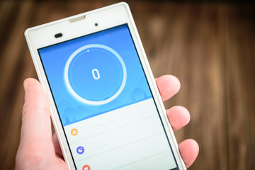 Hand holding phone mobile blank screen. Smart phone on wooden table background with copy space.