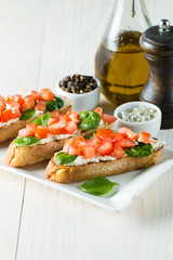 Tomato and cheese fresh made bruschetta. Italian tapas, antipasti with vegetables, herbs and oil on grilled ciabatta and baguette bread. Sandwich.