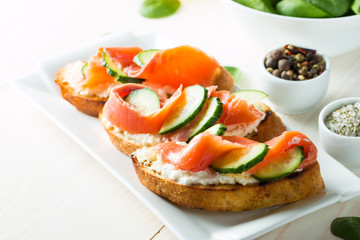 Salmon, cucumber and cream cheese bruschetta. Italian tapas, antipasti with vegetables, herbs and oil on grilled ciabatta and baguette bread. Sandwich.