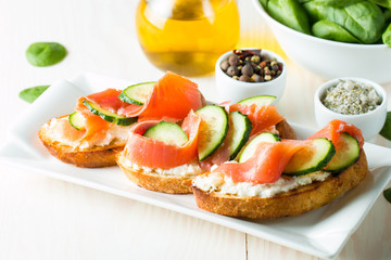 Salmon, cucumber and cream cheese bruschetta. Italian tapas, antipasti with vegetables, herbs and oil on grilled ciabatta and baguette bread. Sandwich.