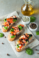 Tomato and cheese fresh made bruschetta. Italian tapas, antipasti with vegetables, herbs and oil on grilled ciabatta and baguette bread. Sandwich.