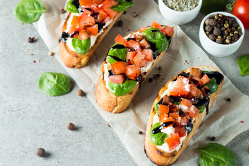 Tomato and cheese fresh made bruschetta. Italian tapas, antipasti with vegetables, herbs and oil on grilled ciabatta and baguette bread. Sandwich.