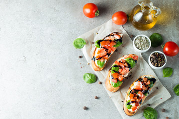 Tomato and cheese fresh made bruschetta. Italian tapas, antipasti with vegetables, herbs and oil on grilled ciabatta and baguette bread. Sandwich.