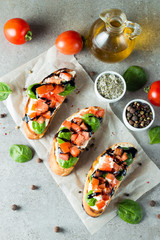 Tomato and cheese fresh made bruschetta. Italian tapas, antipasti with vegetables, herbs and oil on grilled ciabatta and baguette bread. Sandwich.