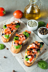 Tomato and cheese fresh made bruschetta. Italian tapas, antipasti with vegetables, herbs and oil on grilled ciabatta and baguette bread. Sandwich.
