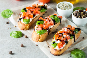 Tomato and cheese fresh made bruschetta. Italian tapas, antipasti with vegetables, herbs and oil on grilled ciabatta and baguette bread. Sandwich.