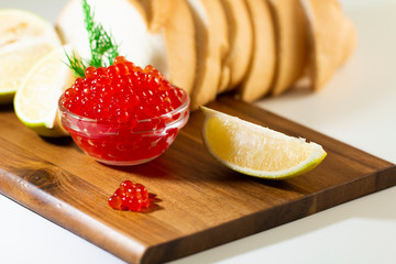 red caviar in glassware on wooden background with space for text