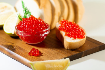 red caviar in glassware on wooden background with space for text