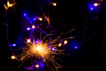 festive background with sparkler and new year lights closeup