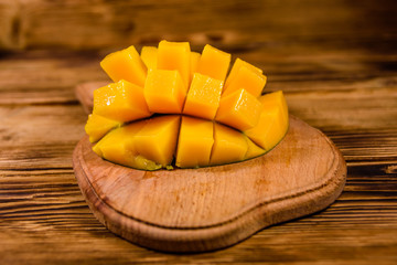 Cutting board with chopped mango fruit on a wooden table