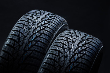 Set of new winter tires on black background with contrasty lighting. Close up product photograph of...