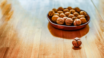 One nut at the table and nuts in wooden plate are separatly