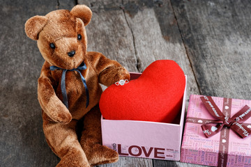 Toy bear doll and the jewelry ring with red heart.