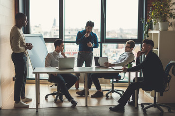 Multiethnic business men dressed in casual trendy wear debating vivaciously during working meeting in conference room, panoramic view