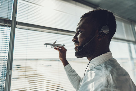 Smiling dispatcher with plane model near window