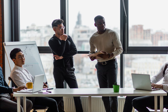 Multi ethnic business person group in casual wear listen to the Asian young man business officer explaining matter to his project team in modern office. Project and Business concept.