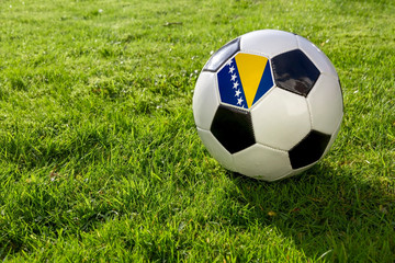 Plakat Football on a grass pitch with Bosnia Herzegovina Flag.