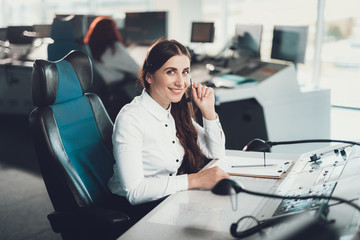 Young female air dispatcher sitting on operator place