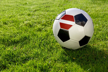 Fototapeta na wymiar Football on a grass pitch with Latvia Flag