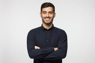 Smiling attractive business man in deep blue shirt isolated on gray background