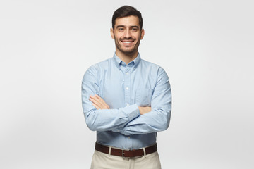 Modern business man in casual blue shirt standing with crossed arms, isolated on gray background - Powered by Adobe