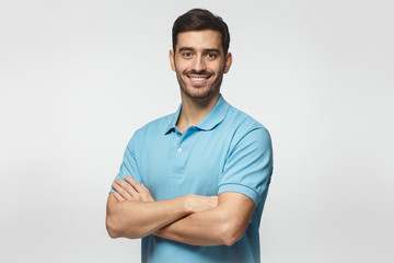 Portrait of young european caucasian man isolated on gray background, standing in blue polo shirt...