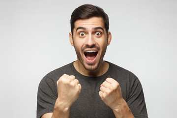 Soccer fan concept. Young attractive man shouting while his team win, raised both fist in victory...