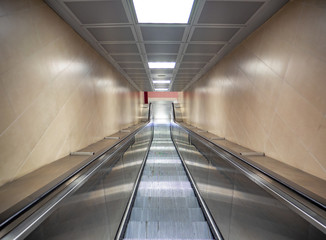 escalator in a train station lit by neon light