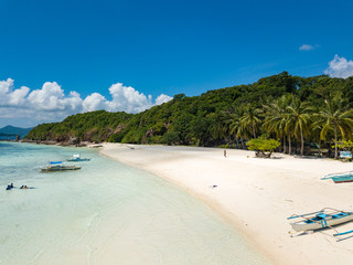 Aerial view of tropical beach on the island Malcapuya. Beautiful tropical island with sand beach, palm trees. Tropical landscape with shore and boat. Palawan, Philippines