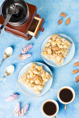 Two coffee cups, coffee grinder and apple pie on blue artistic background.