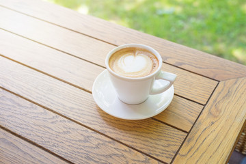 Morning cup of cappuccino on wooden table.