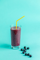 blackberry smoothies in glass with a straw isolated on the blue background. close up photo. juice from figs, prunes, beetroot