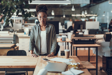 Beautiful afro american girl standing near wooden table at modern office