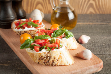 Italian tomato and cheese bruschetta. Tapas, antipasti with chopped vegetables, herbs and oil on grilled ciabatta and baguette bread.
