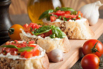Italian tomato and cheese bruschetta. Tapas, antipasti with chopped vegetables, herbs and oil on grilled ciabatta and baguette bread.
