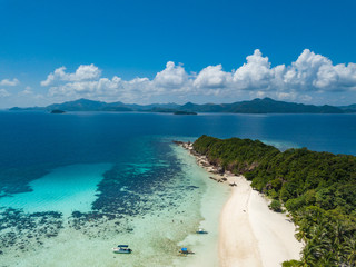 Aerial view of tropical beach on the island Malcapuya. Beautiful tropical island with sand beach, palm trees. Tropical landscape with shore and boat. Palawan, Philippines