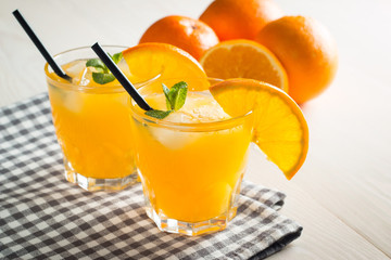 Photo of fresh orange juice in the glass jar. Summer healthy organic drink concept. Cold beverages with ice and orange fruits.