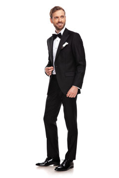 handsome businessman in black suit looks to side while standing