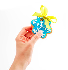 Female hand holding cookie in a shape of blue snowflake, isolated on white. Christmas holiday decoration, winter time food.