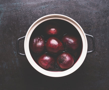 Whole boiled beets in cooking pot on dark background, top view. Healthy clean, low calories food and diet eating concept