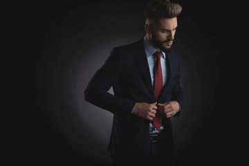 attractive businessman buttons navy suit and looks down to side