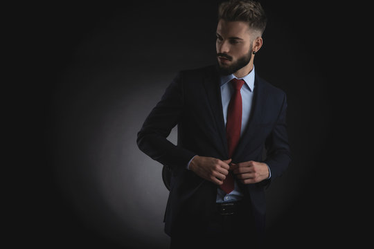 portrait of curious businessman unbuttoning suit and looking to side