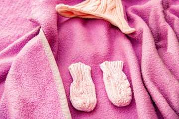 Children's knitwear, a hat and socks for a newborn baby on a lilac bed.