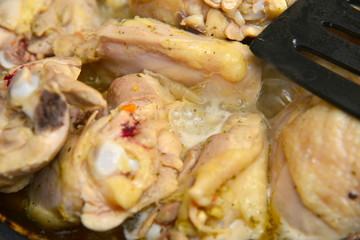The cook mixes fried chicken in a pan with butter and spices.
